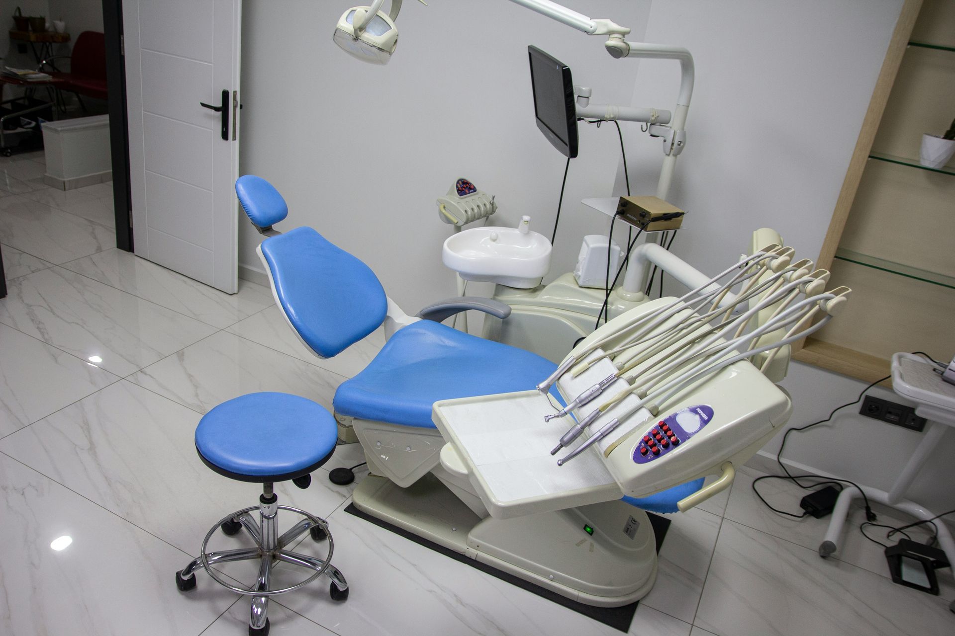 Dental office interior with blue dental chair, tools, and equipment.