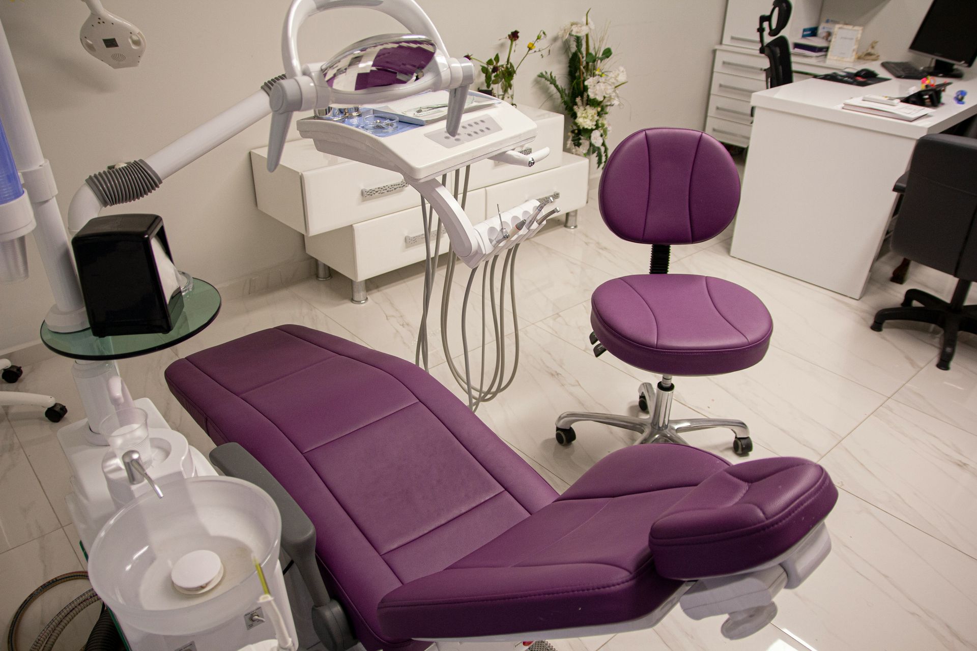 Purple dental chair in modern, well-lit dental office, with dental equipment.