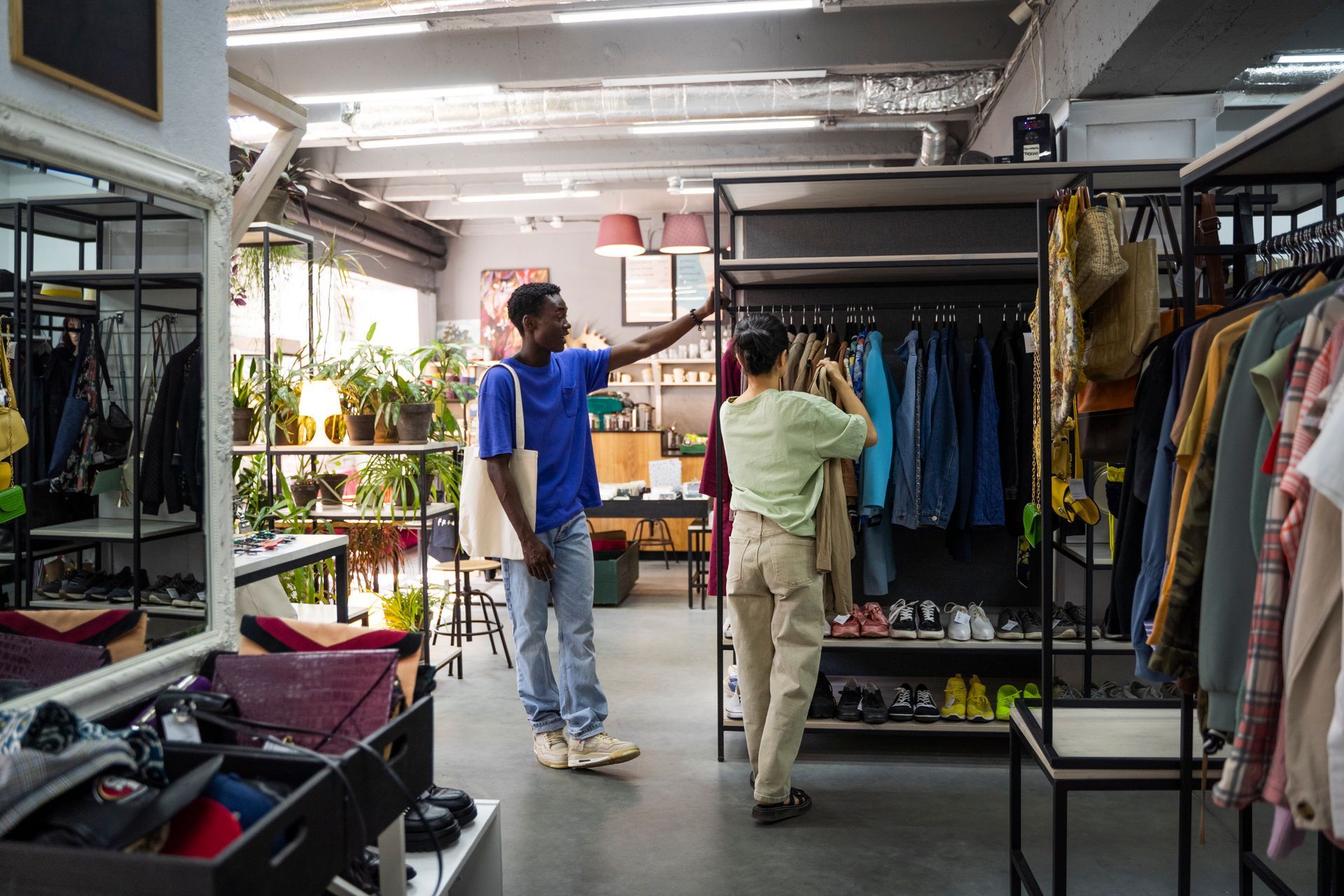 Two people browse clothes racks in a brightly lit clothing store.