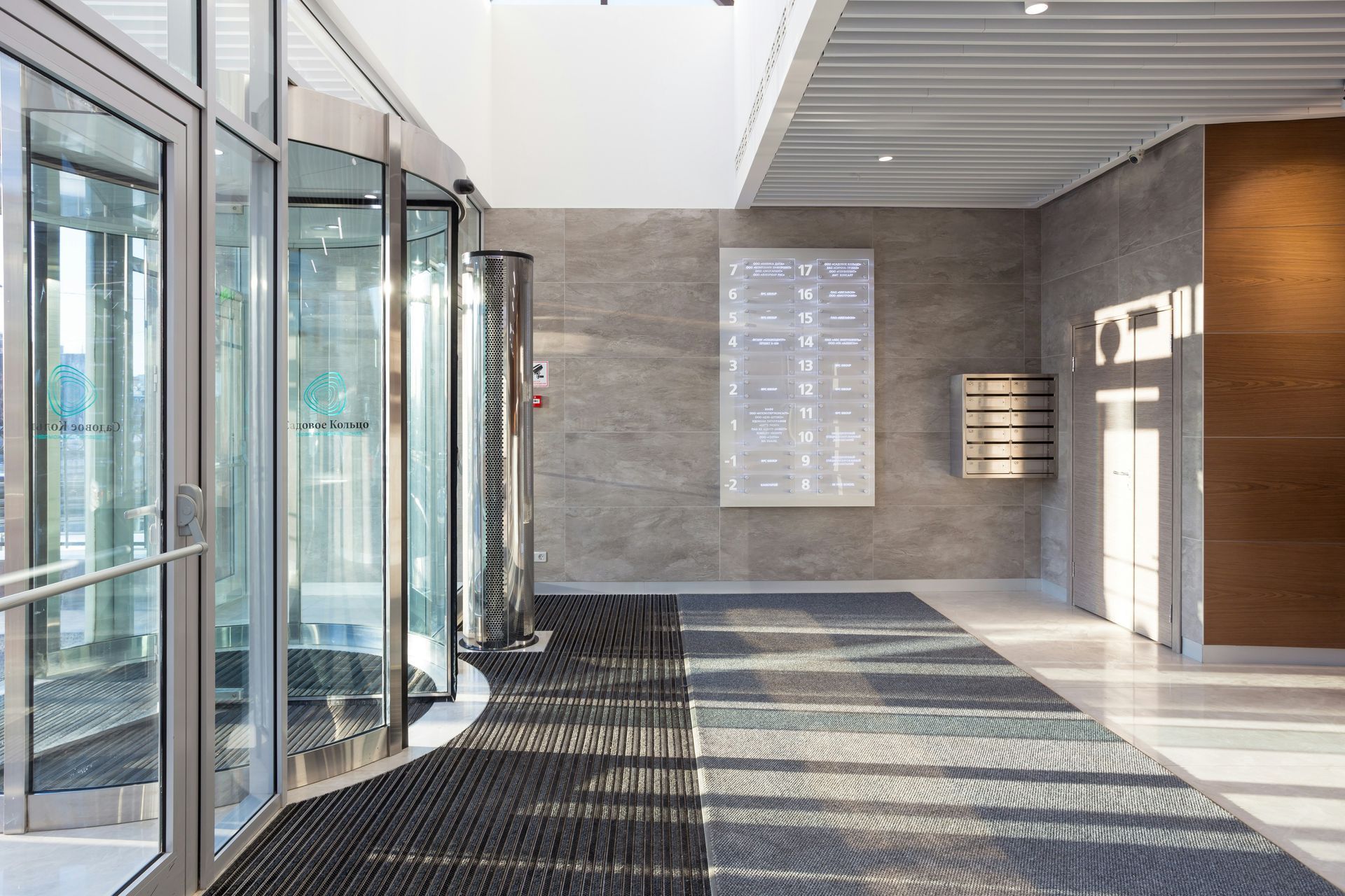 Revolving glass door entrance with gray mat, office interior with directory sign.