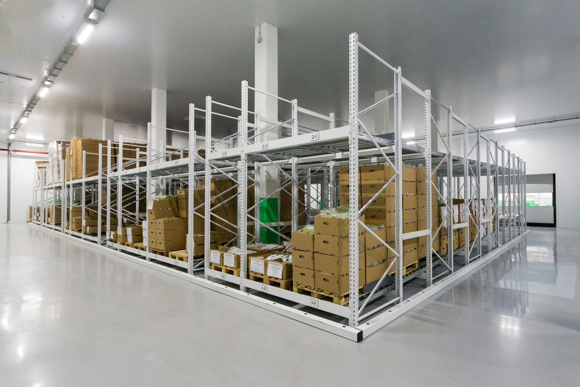 Warehouse storage racks filled with cardboard boxes in a bright white room.