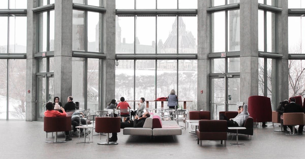Large modern lobby with glass walls; people sit on red and gray furniture, overlooking a snowy outdoor scene.