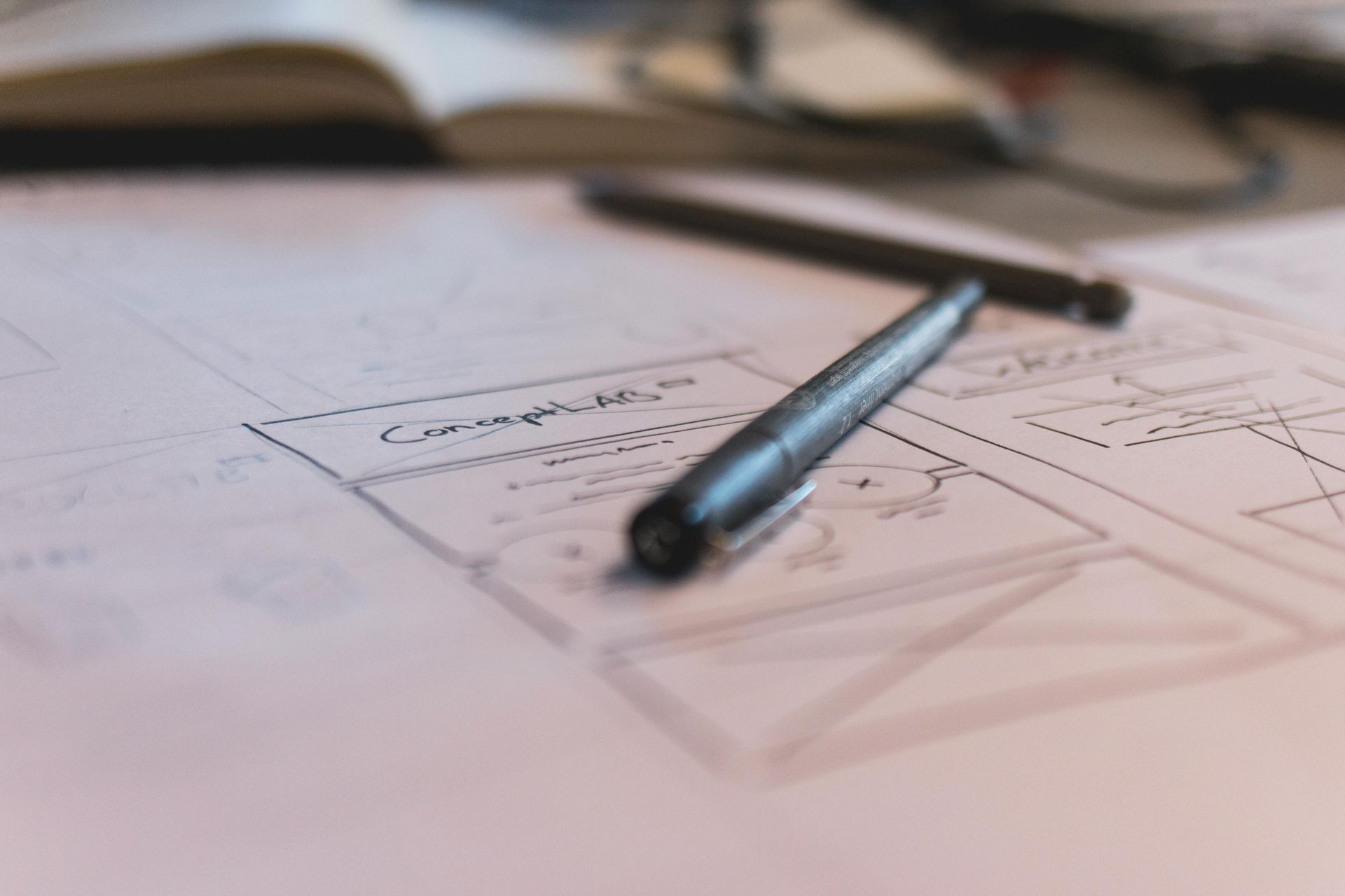 Pen on a blueprint sketch with handwritten notes, suggesting design or planning.
