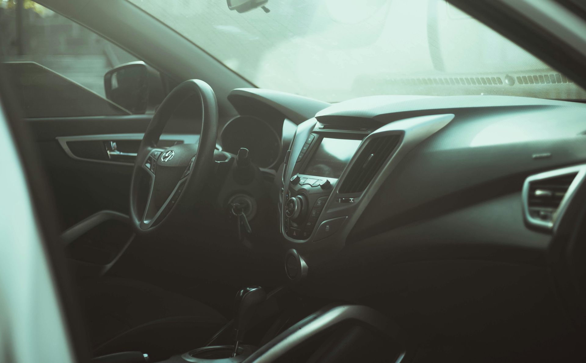 Interior view of a car's dashboard and steering wheel, bathed in sunlight.