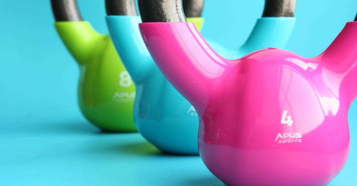 Three colorful kettlebells: green, blue, and pink, arranged diagonally on a blue background.