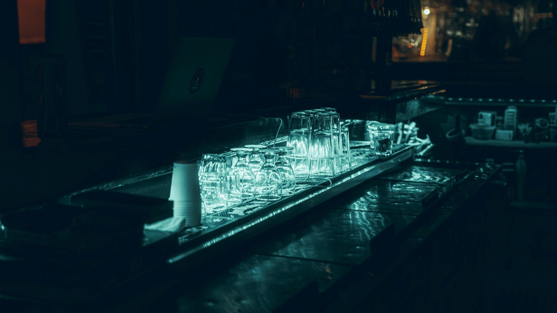 Lit ice sculpture of a ship in dark setting with teal lighting.