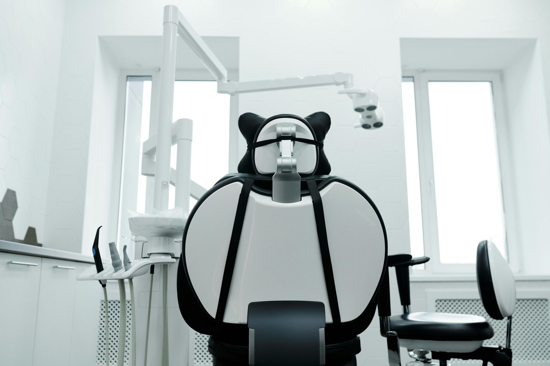 Dental chair in a bright, modern office setting with medical equipment and large windows.