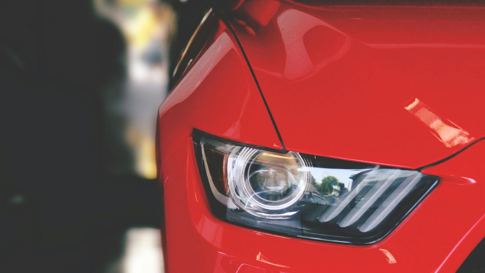 Red car headlight and hood detail, close-up.