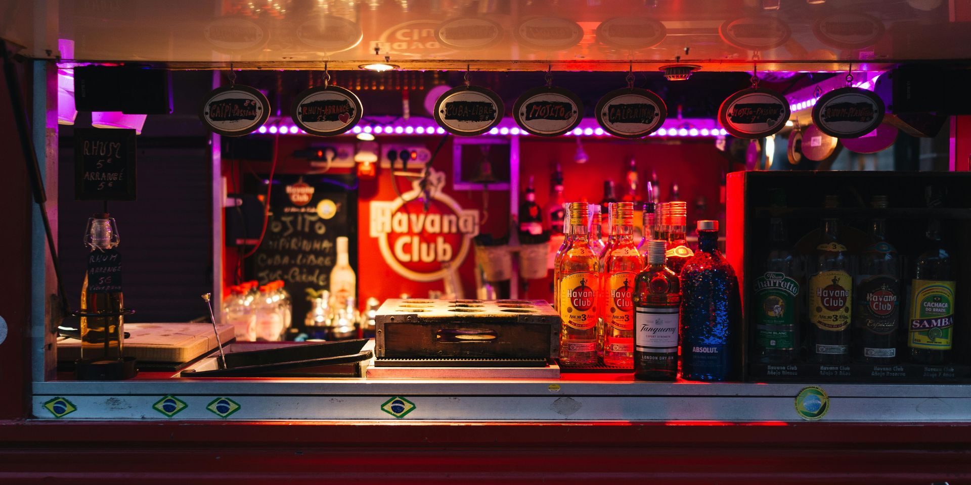 Bar interior with bottles of liquor, a Havana Club sign, and overhead lights.
