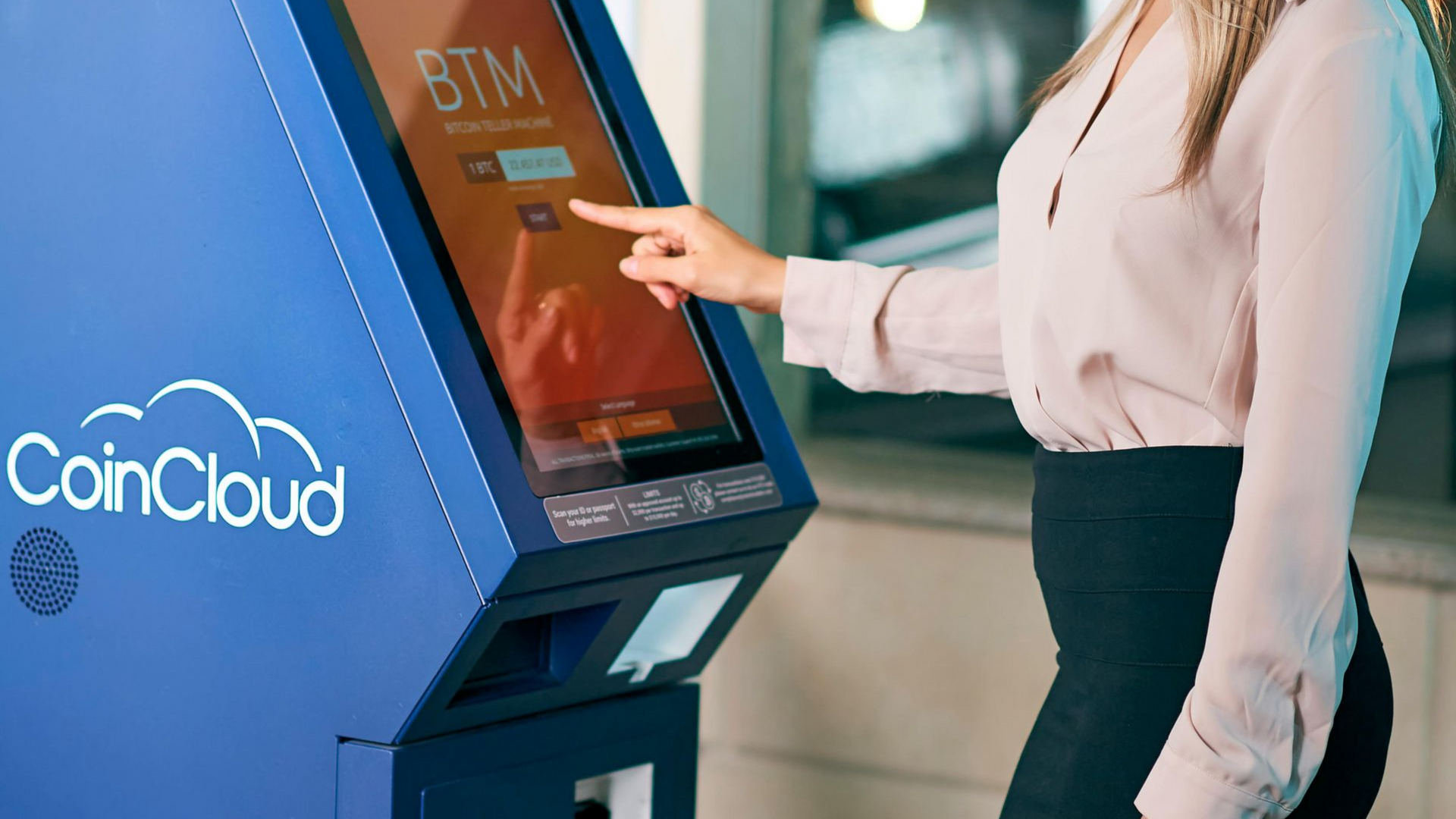 Woman using a blue CoinCloud Bitcoin ATM, touching the screen.