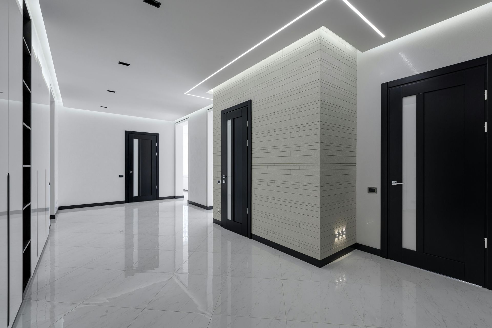 Modern interior hallway with glossy white floor, black doors, and recessed lighting.