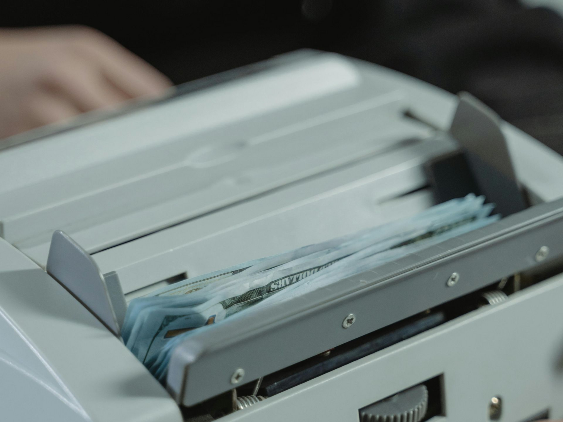 Money counting machine with a stack of paper bills inside.