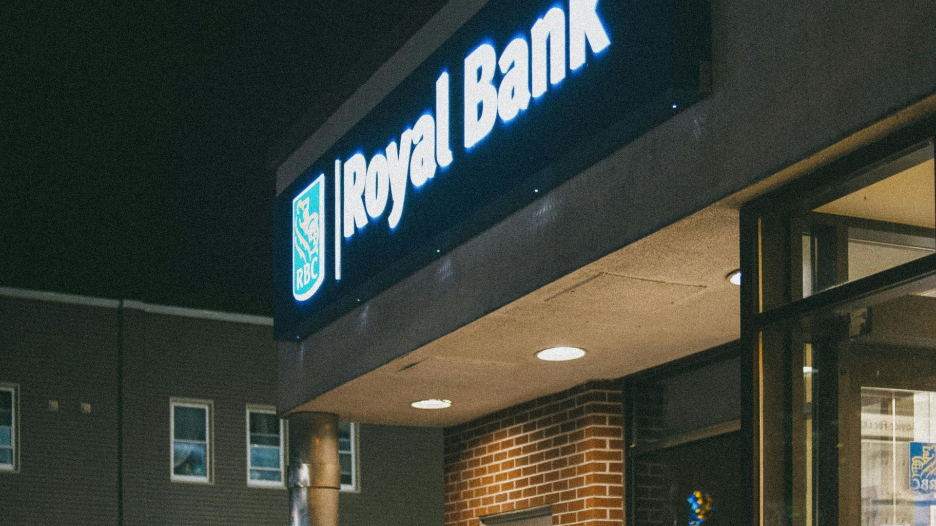 Royal Bank illuminated sign on a brick building at night.
