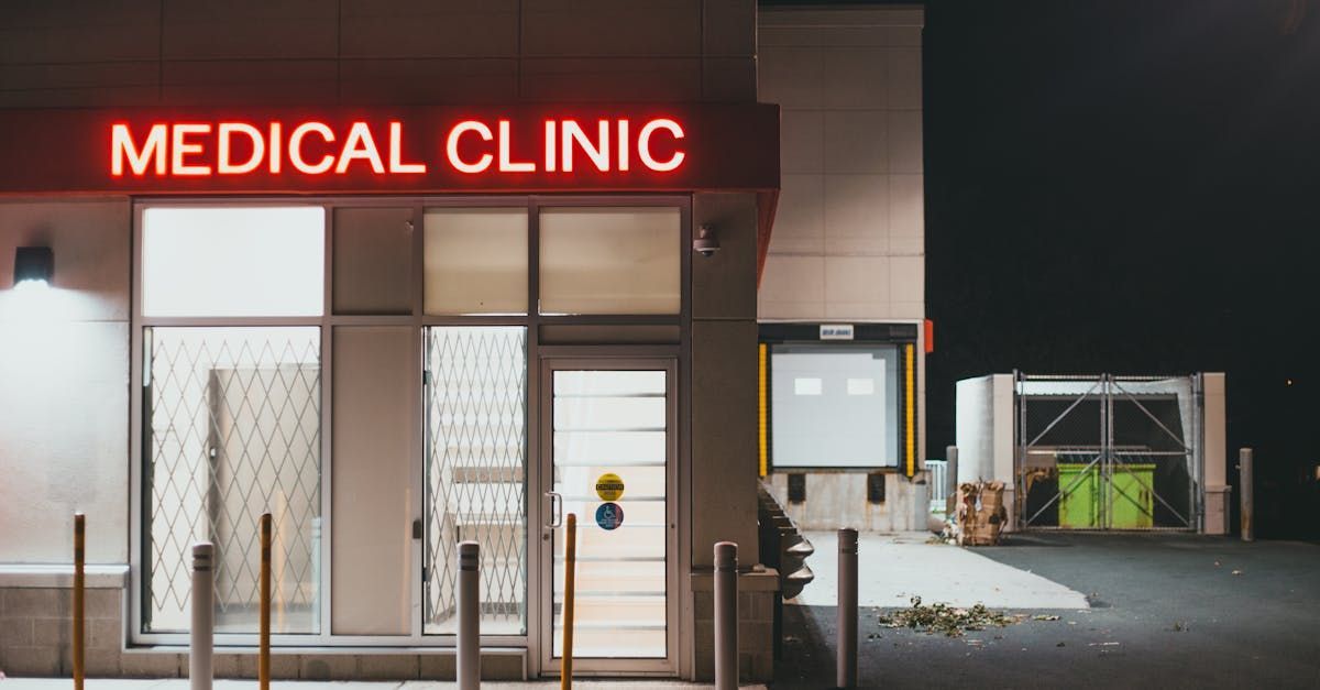 Medical clinic entrance at night, neon sign, glass doors, and loading dock.