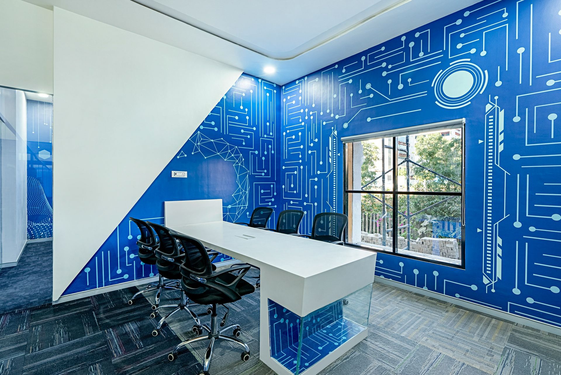 Modern office interior with blue circuit board patterned wall, white table, chairs, and window.