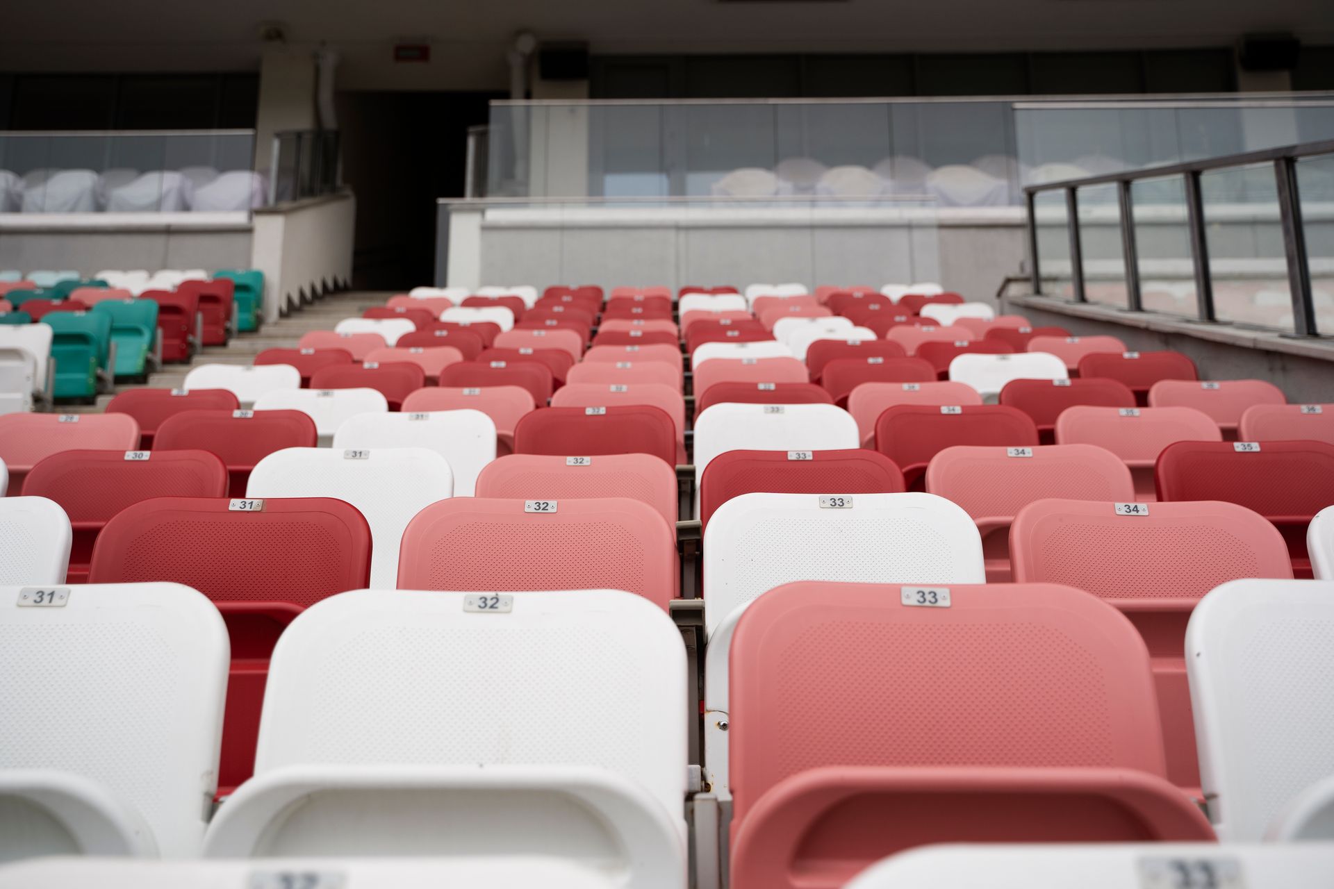 Rows of empty stadium seats in white, red, and pink hues.