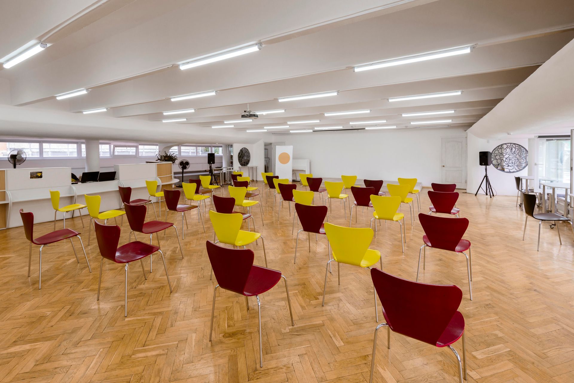 Meeting room with rows of red and yellow chairs, a projector, and speakers.
