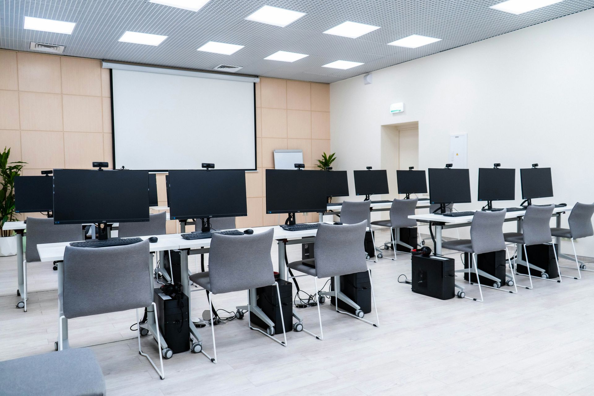 Computer lab with rows of workstations, projector screen, and chairs.