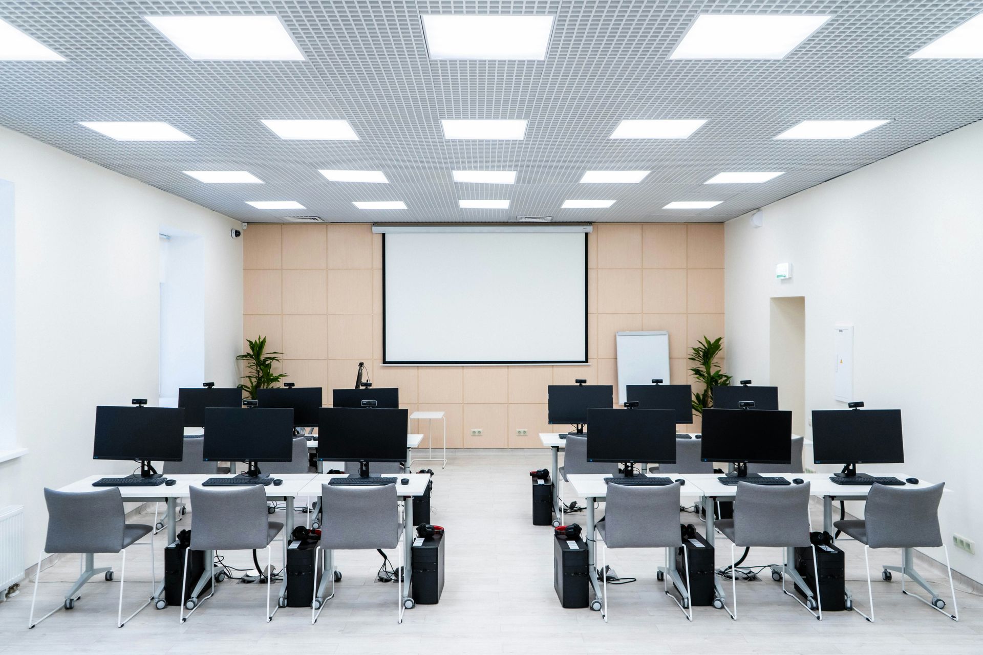 Computer lab with rows of computers, projector screen, and recessed lighting.