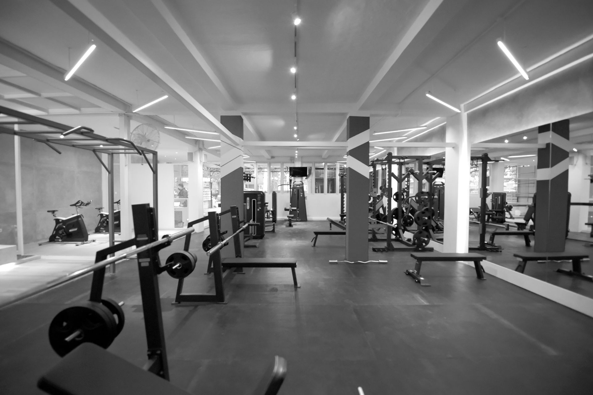 Black and white gym interior with workout equipment and weights.