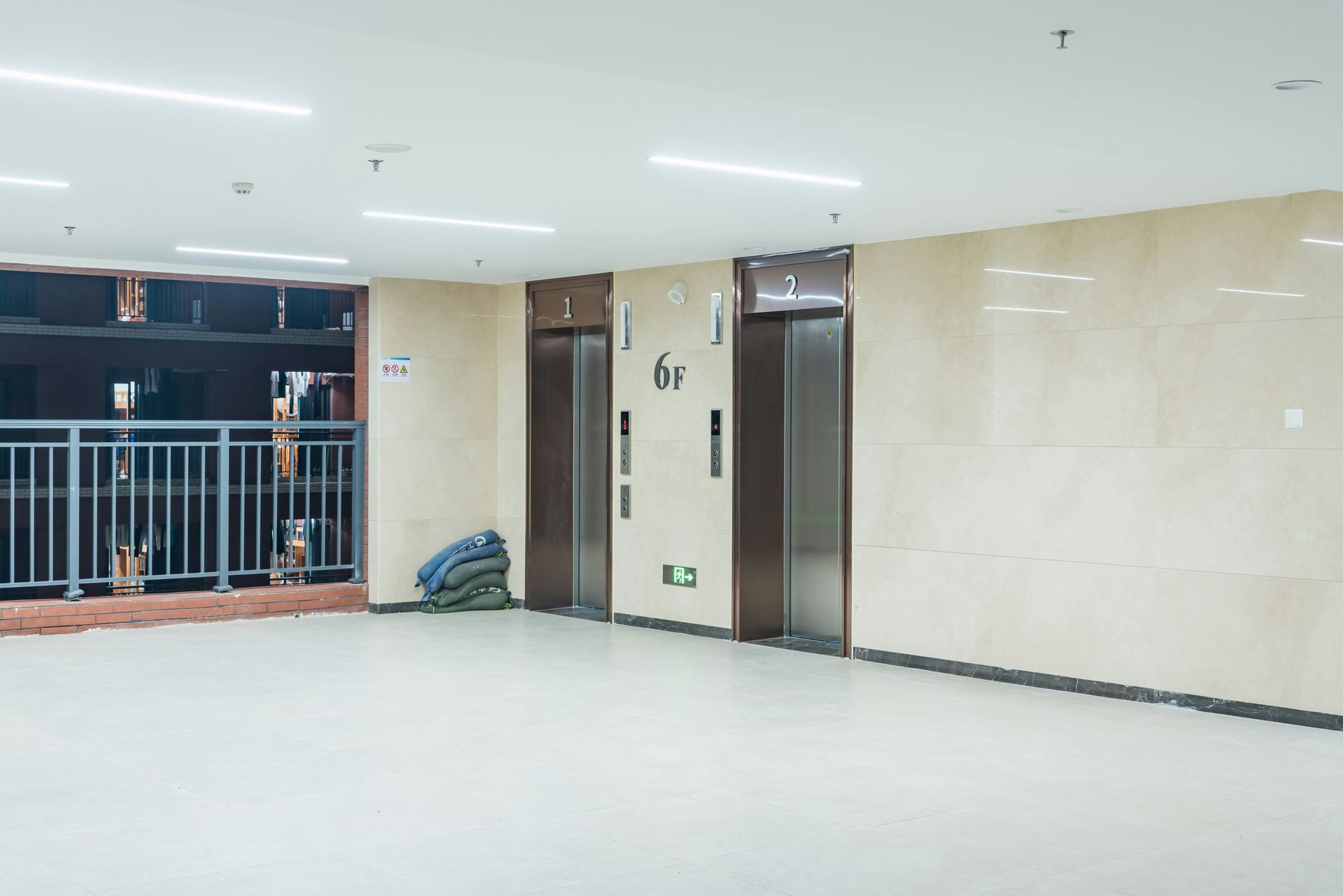 Elevator lobby with two closed elevators, a window, and a bag on the floor.