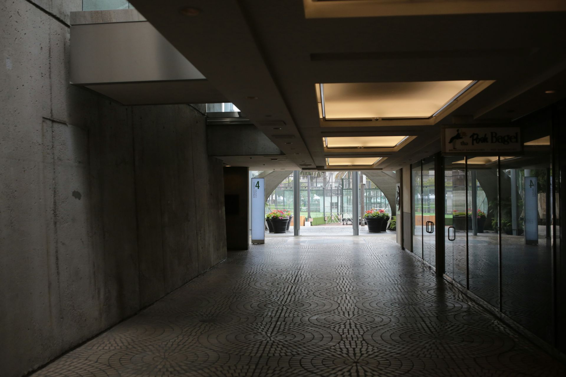 Indoor corridor with tiled floor, concrete walls, and arched glass doorway to exterior.