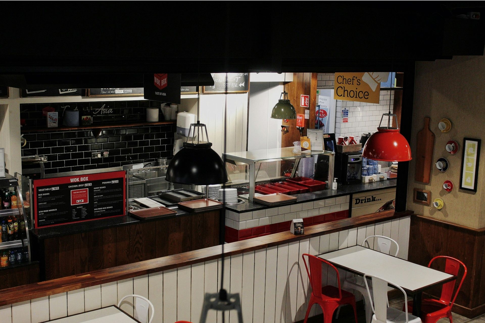Interior shot of a restaurant with a red and white counter, tables, and chairs.