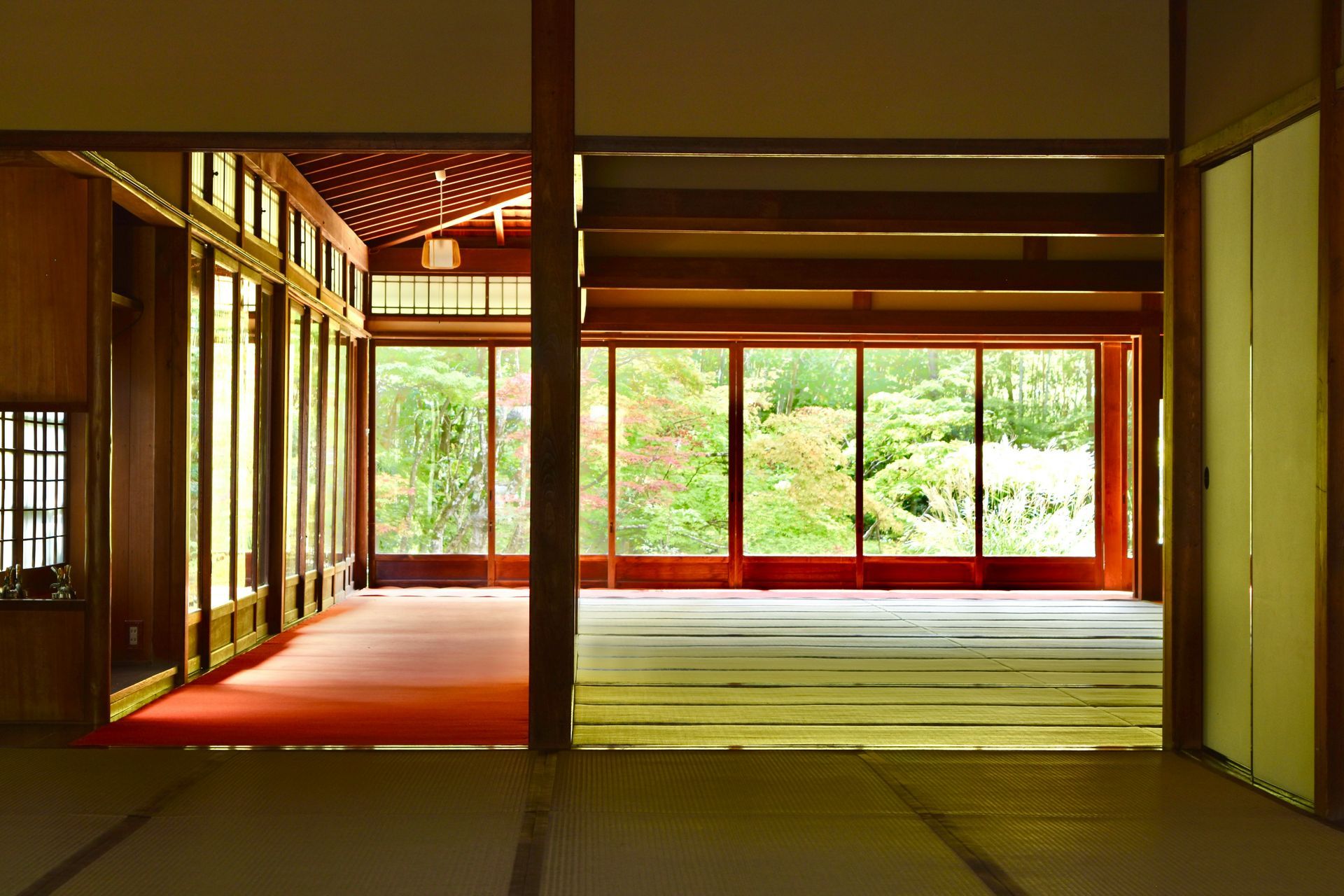 Japanese-style room with wooden frames and large windows overlooking a colorful garden.