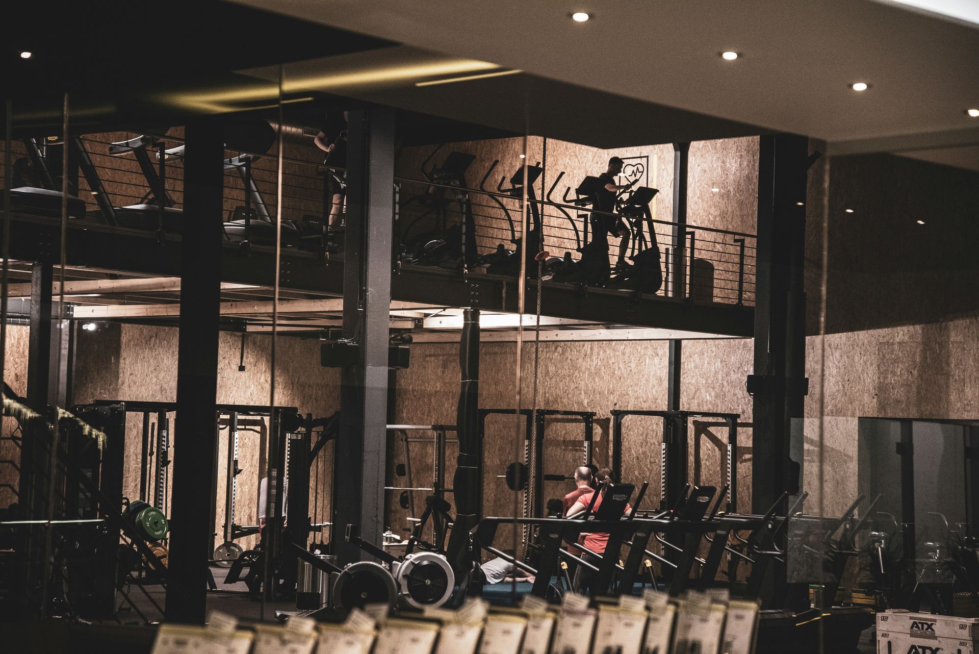 Gym interior with multi-level equipment, a person on a treadmill, and other weight machines.