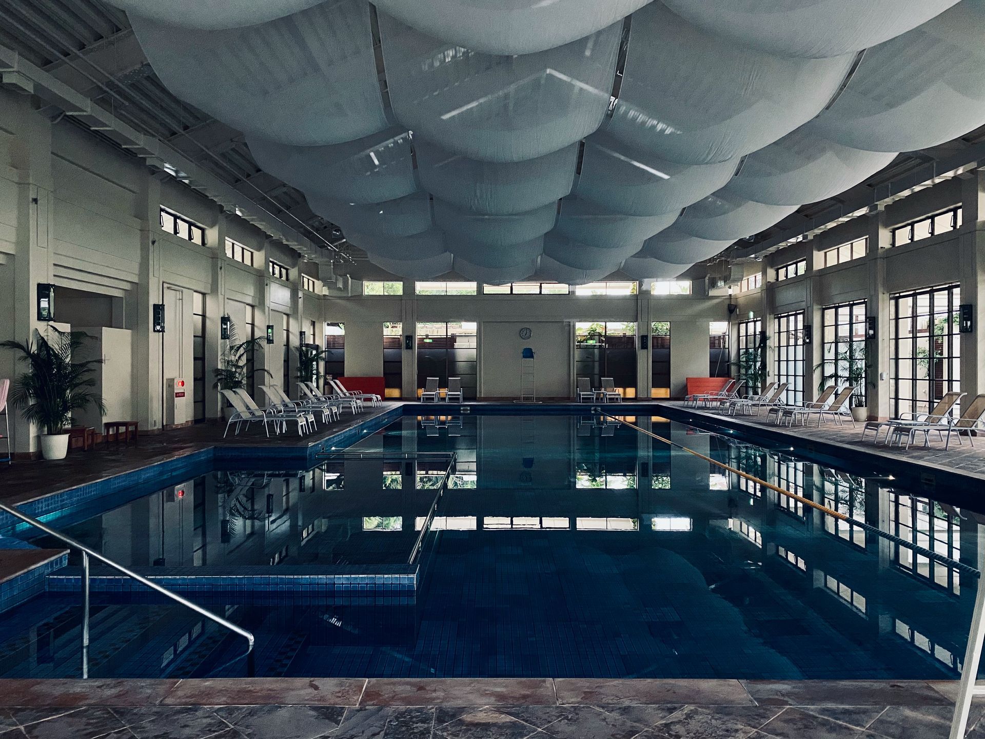 Indoor swimming pool with lounge chairs. A unique bubble-like ceiling decorates the room.