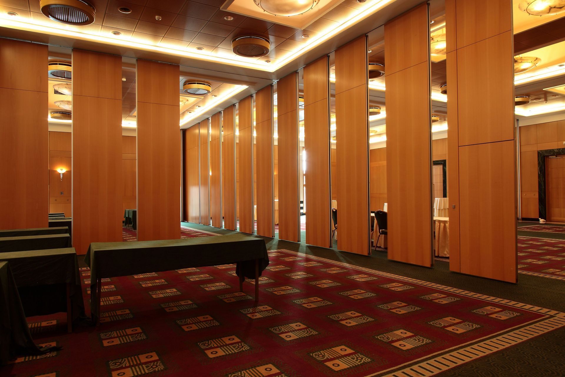 Room with wood panel dividers, dark carpet, and tables covered with green cloths.