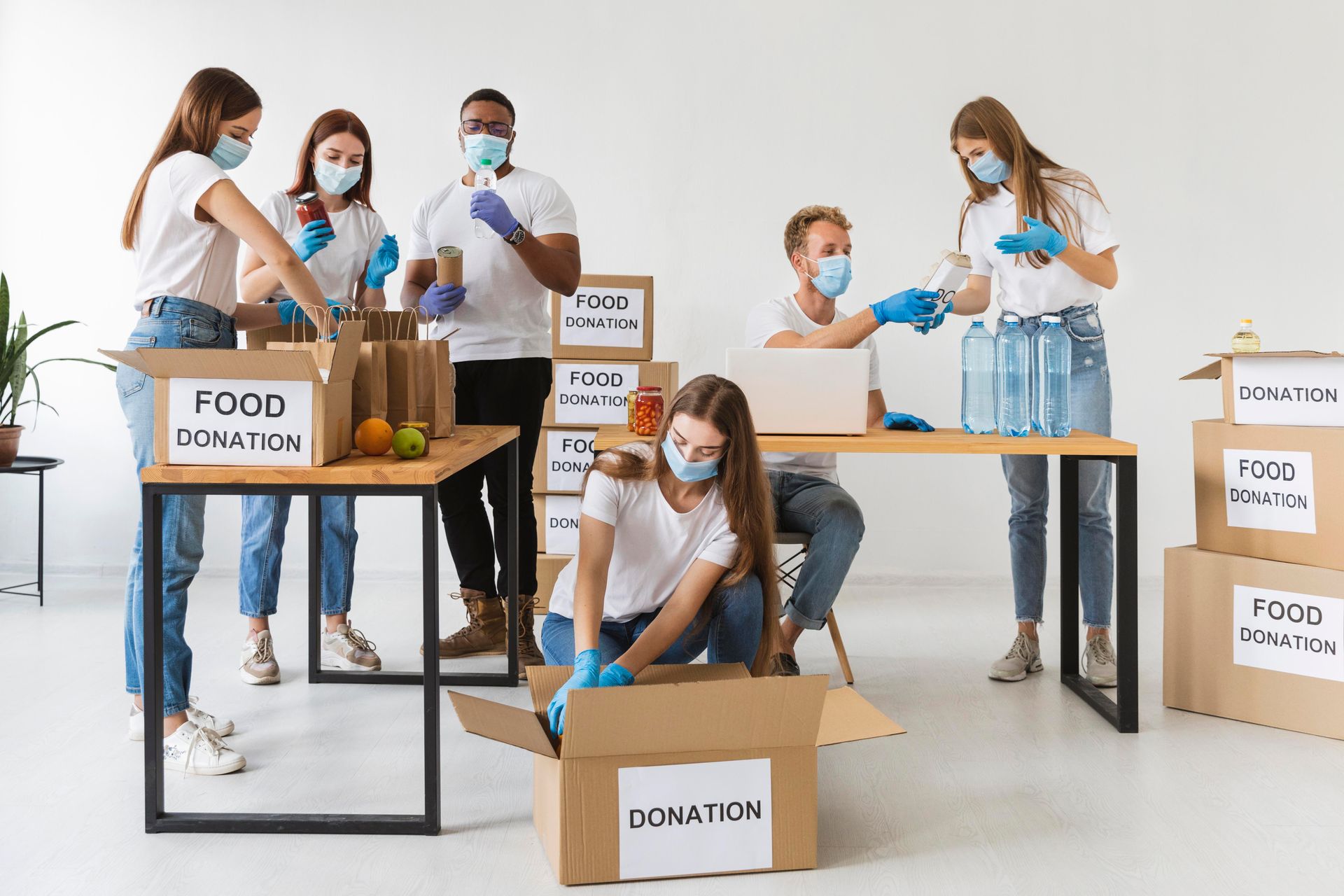 Volunteers wearing masks and gloves packing food donations into boxes.