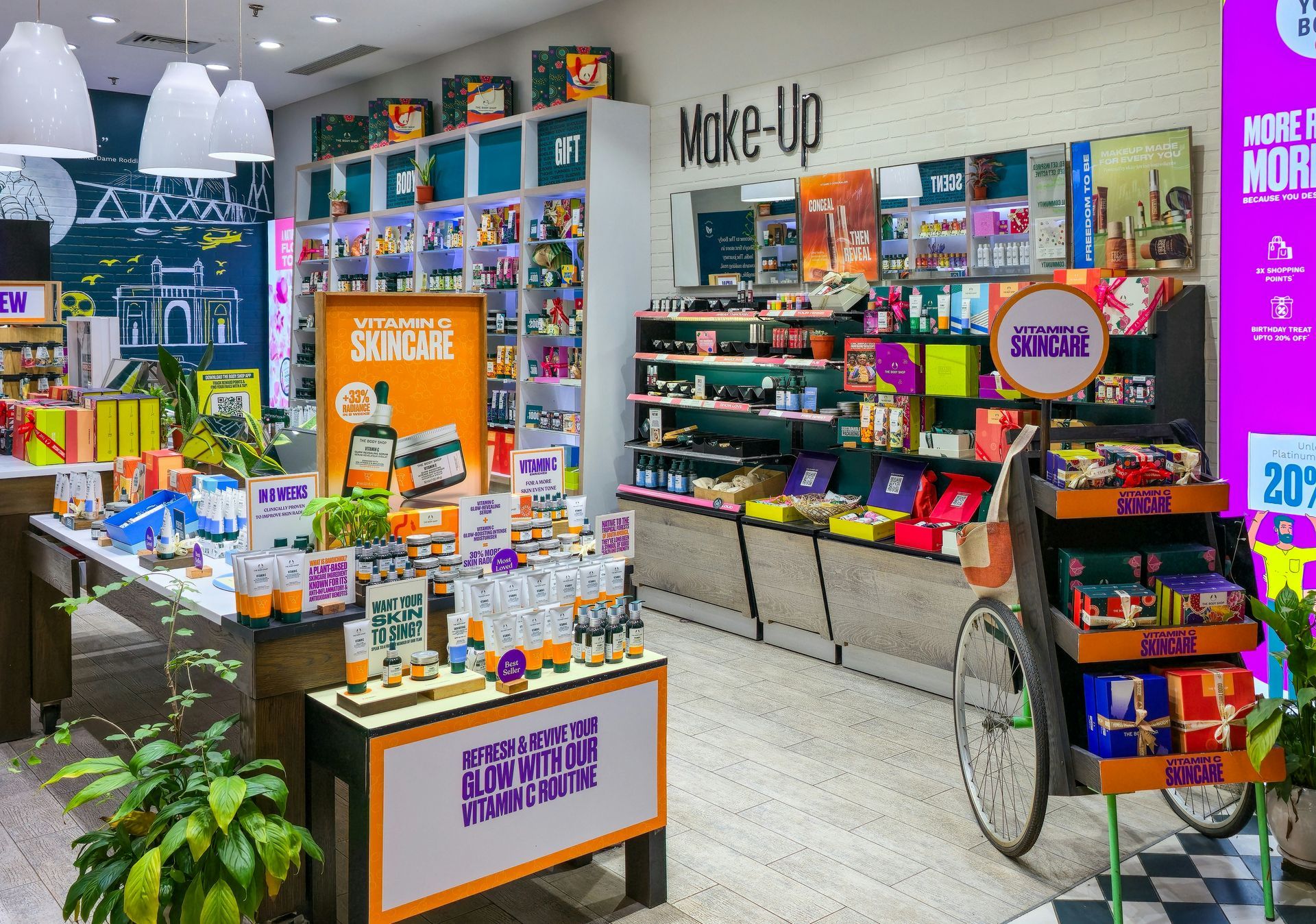 A brightly lit cosmetics store. Shelves stocked with products, colorful displays, and a bicycle-style display stand.