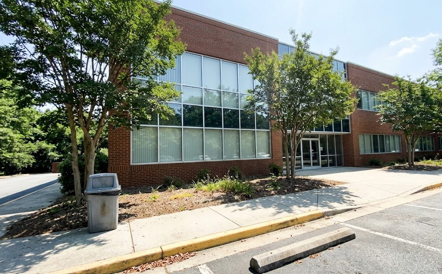 Beautifully trimmed green trees in front of a modern commercial office building in Charlottesville.