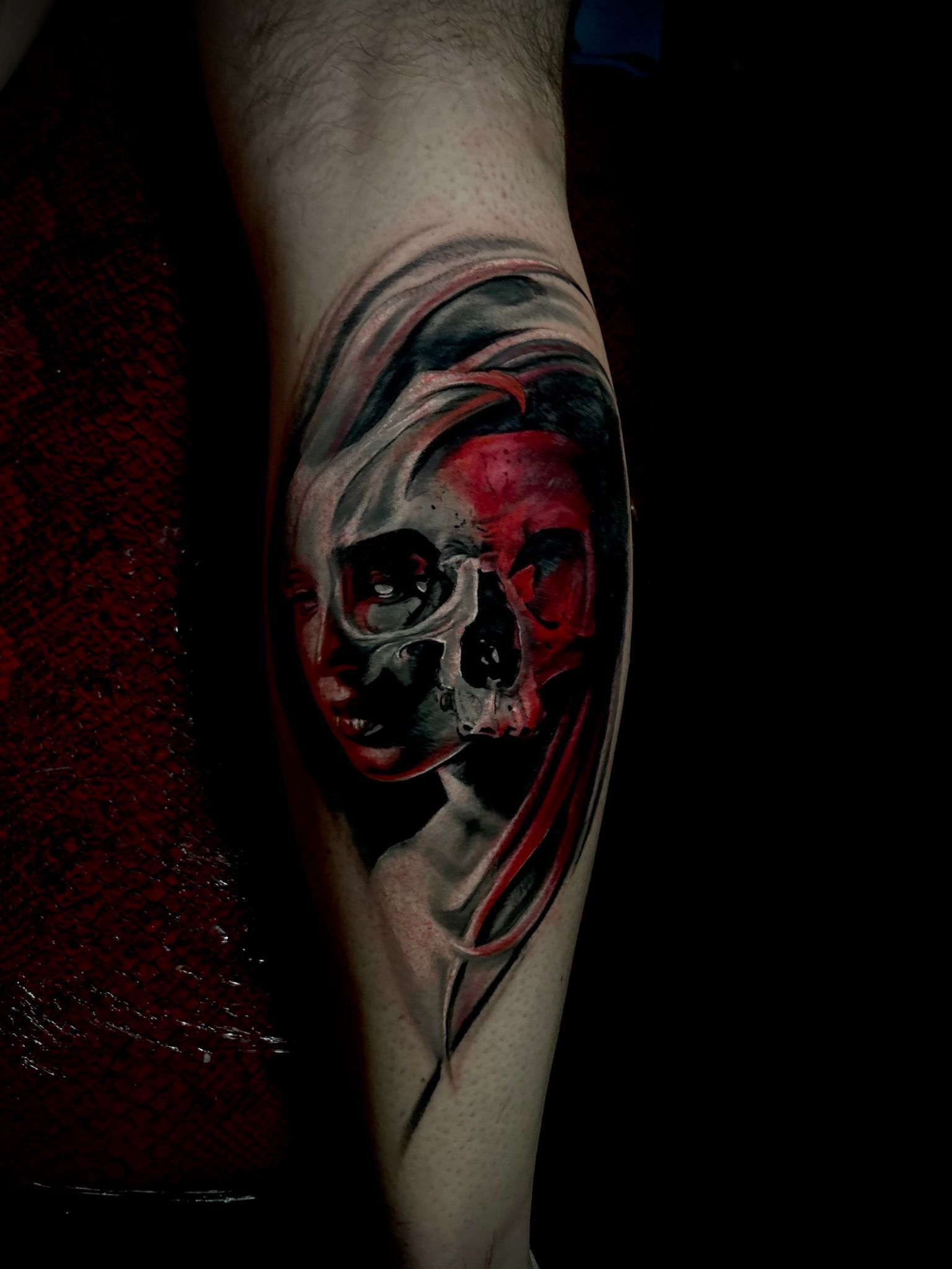 Skull tattoo on a leg. Red and black hues, realistic style.