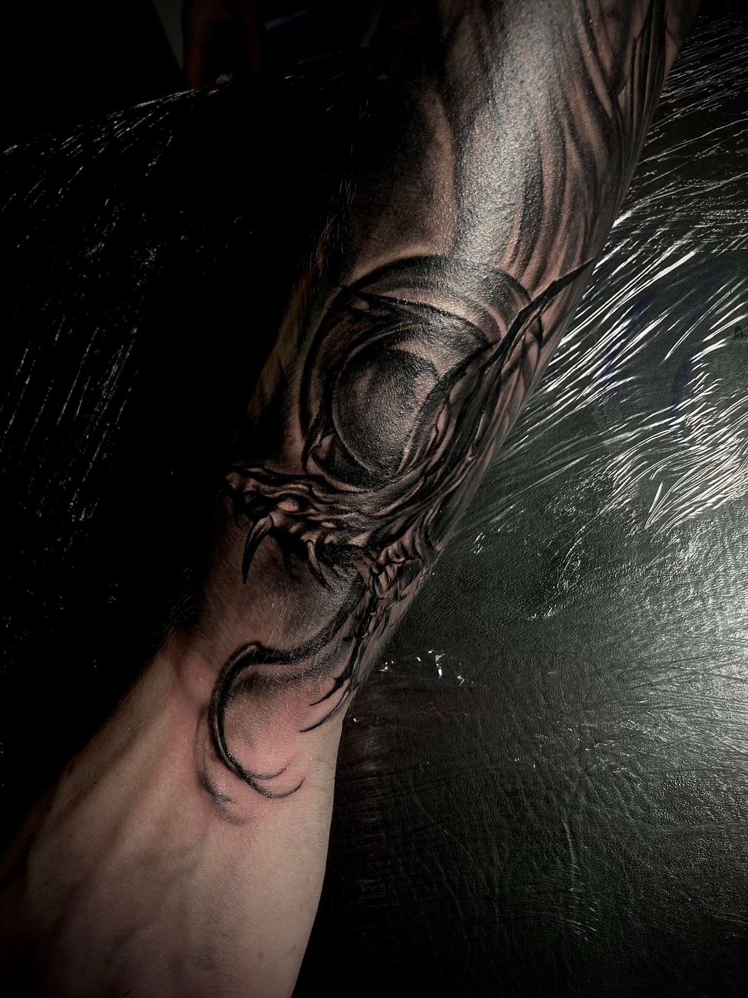 Dark, detailed tattoo of an eye with surrounding abstract, spiky lines on an arm.
