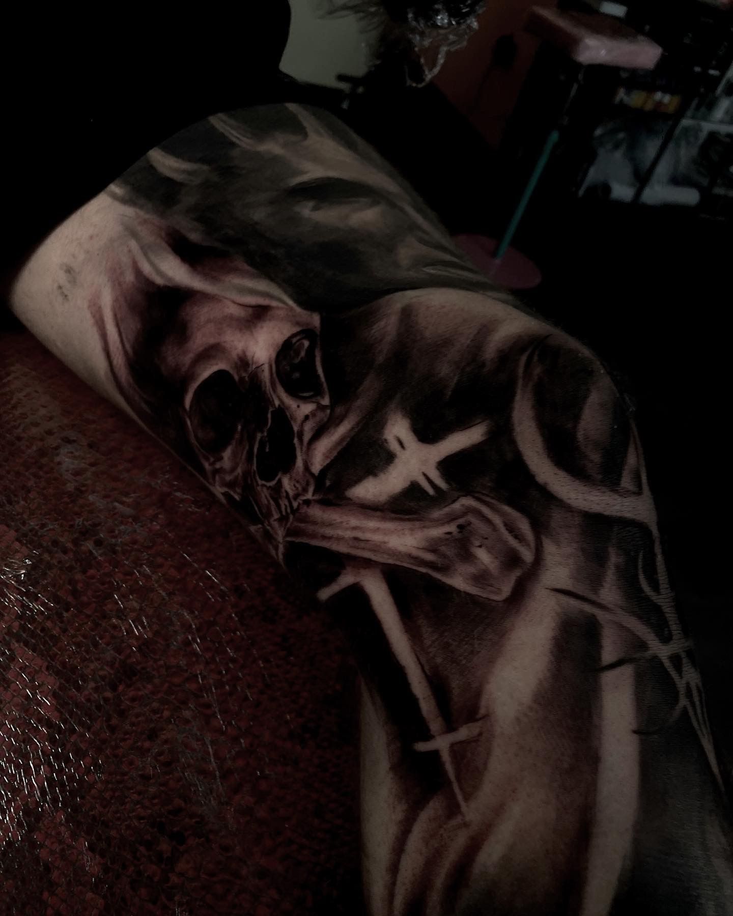 Skull tattoo on an arm, with bones and cross-like shapes in a dark, shaded style.