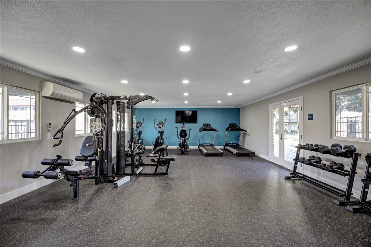A large gym with a lot of equipment and a television on the wall.