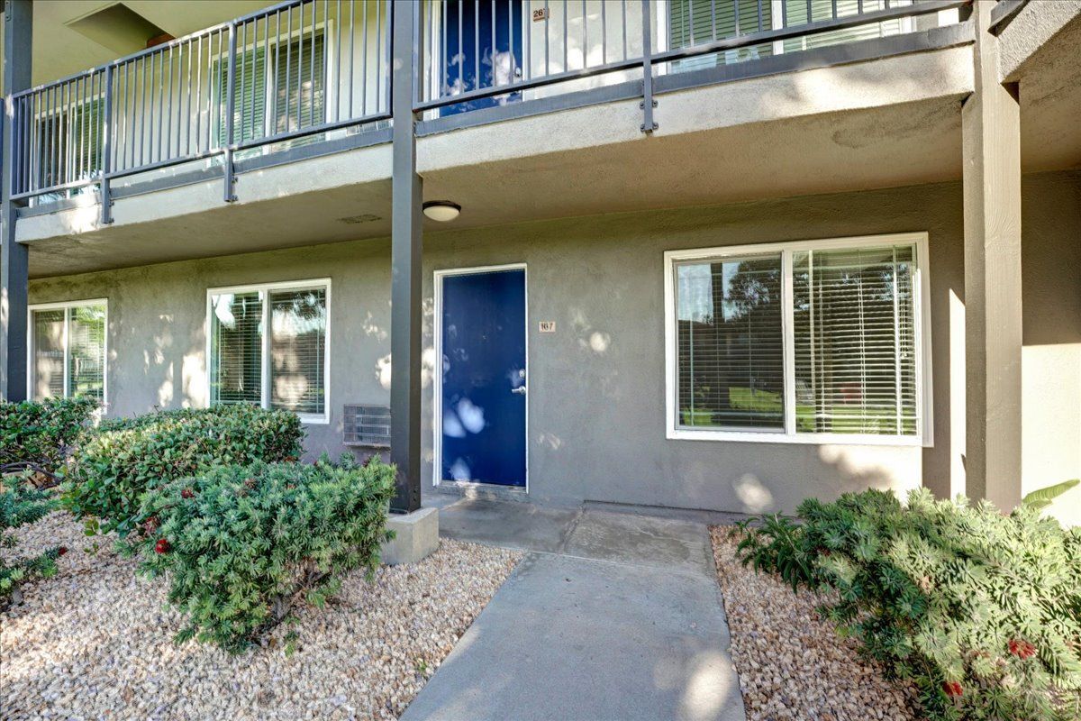 A gray apartment building with a blue door and a balcony.