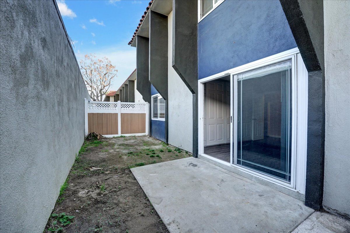 The backyard of a house with a sliding glass door and a fence.