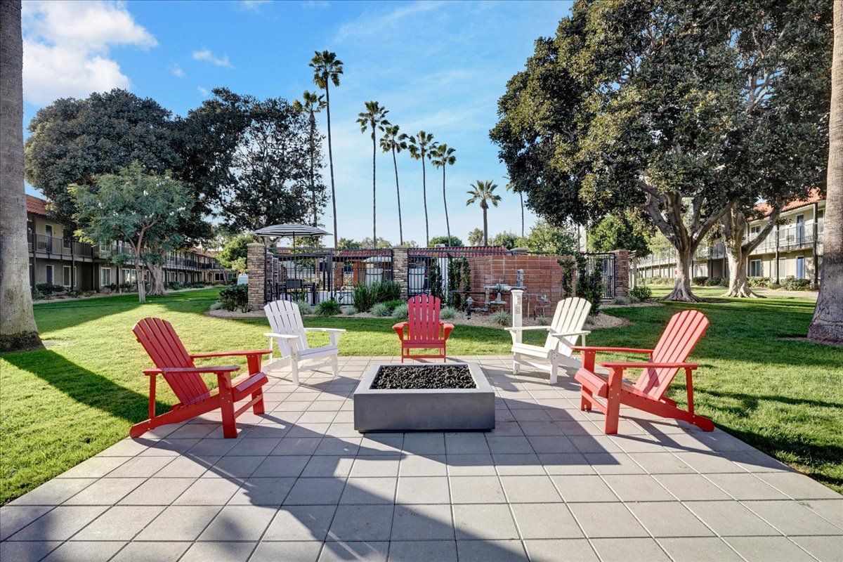 A group of red and white chairs are sitting around a fire pit.