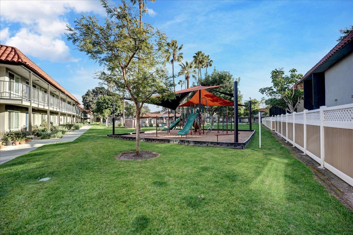 There is a playground in the middle of a lush green park.