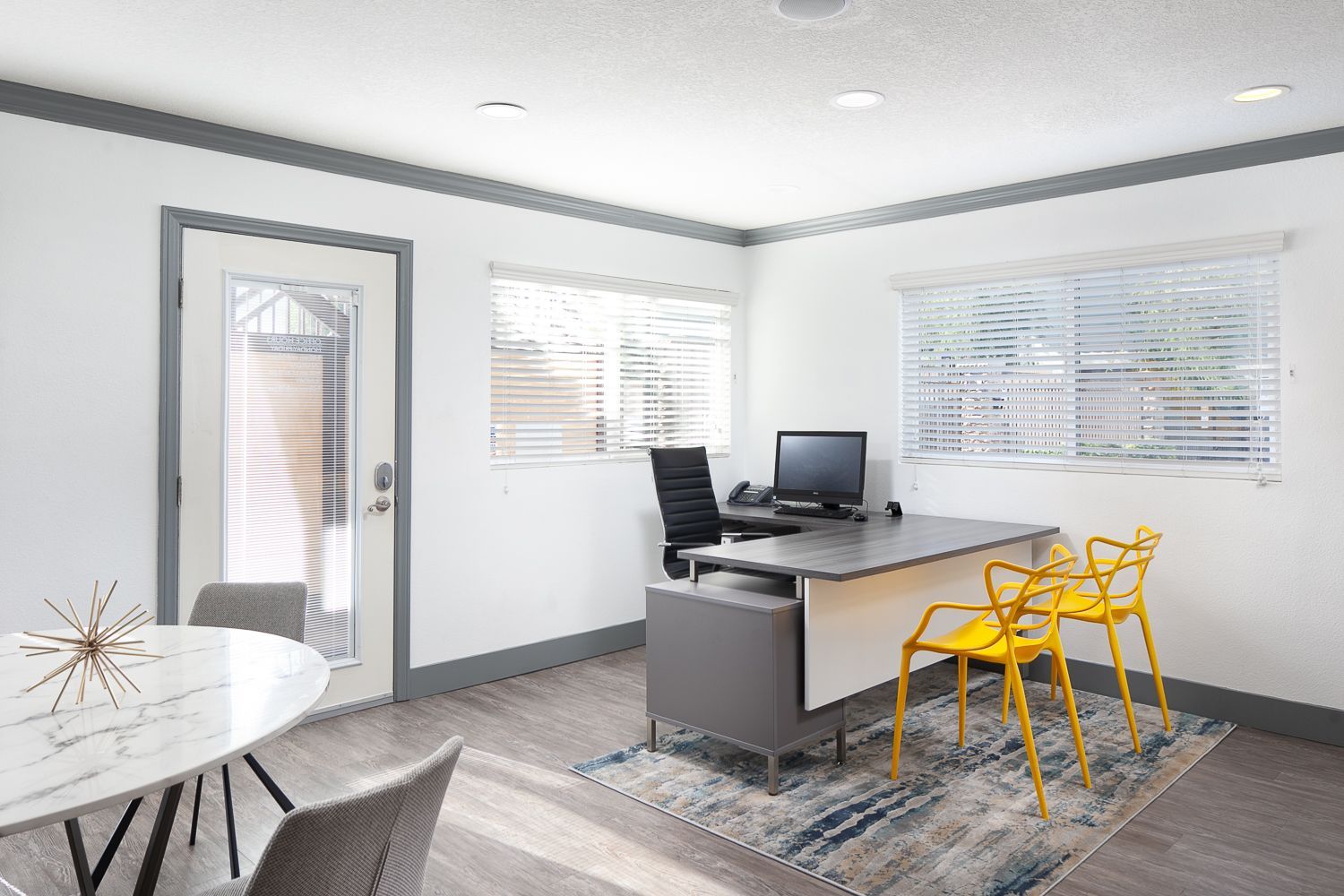 A room with a desk , chairs , a table and a computer.