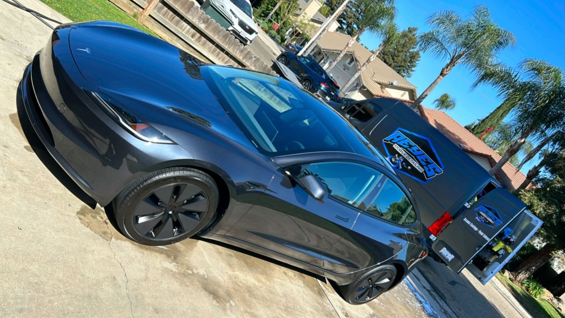 A person is cleaning a black car with a blue cloth.