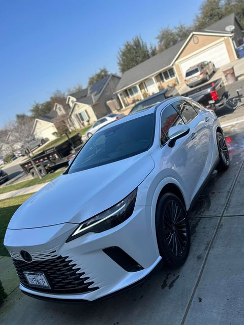 A white car is parked on the sidewalk in front of a house.