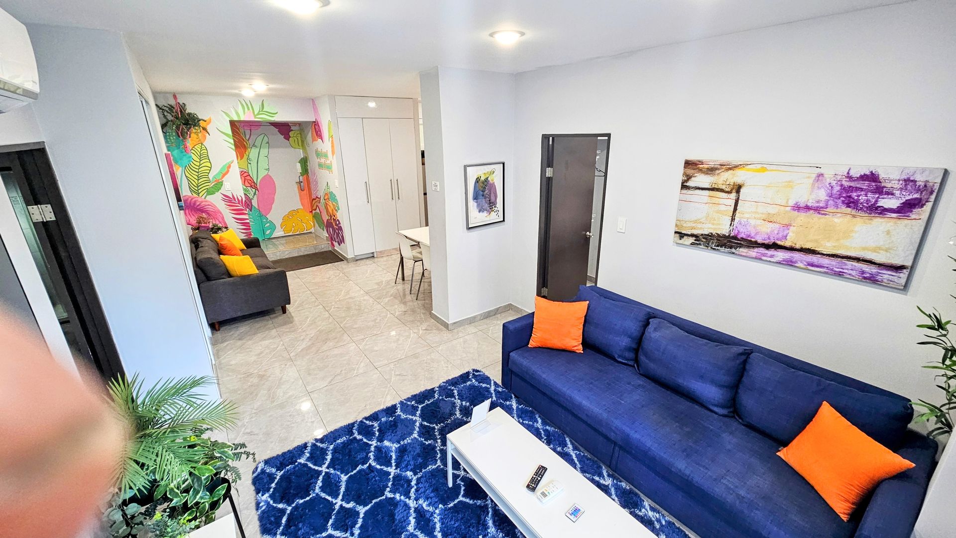 A living room with a blue couch and orange pillows