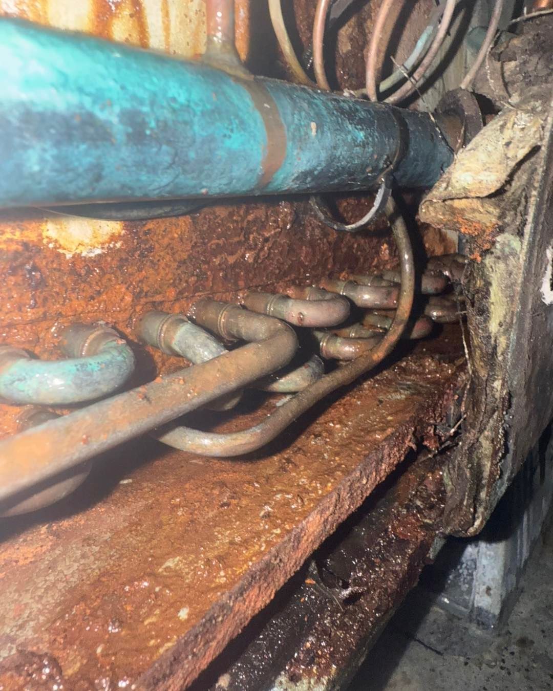 Rusted mechanical equipment with corroded copper tubing and brown discoloration.