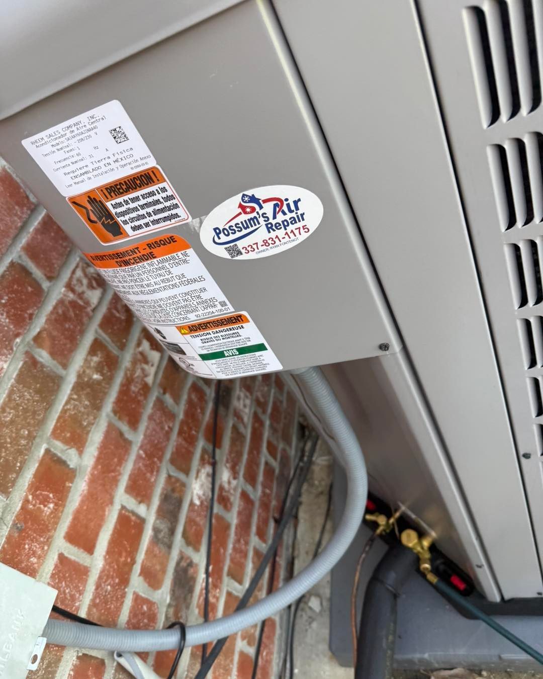 HVAC unit attached to a brick wall, with service ports visible. Gray and silver colors.