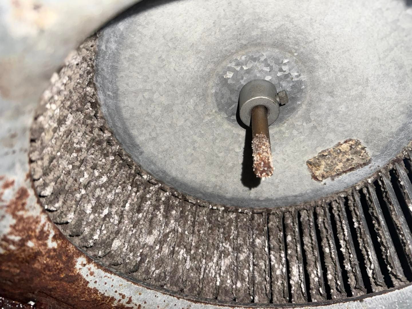 Close-up of a dirty blower fan with caked debris on the blades and central shaft.