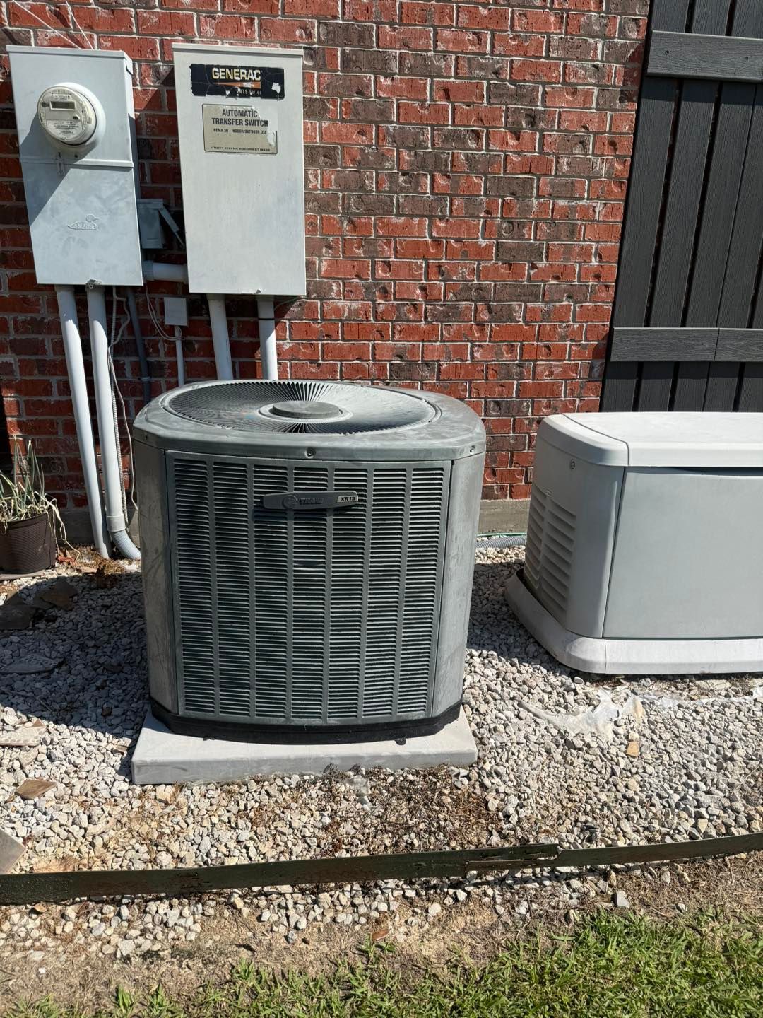 Central air conditioning unit and generator outside a brick building.